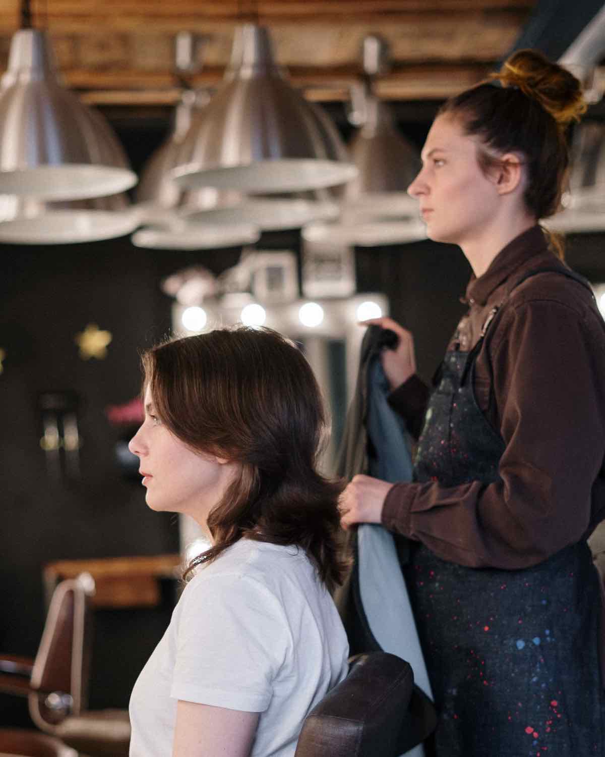 Peluquera atendiendo a una clienta en un salón de estética moderno y cálido